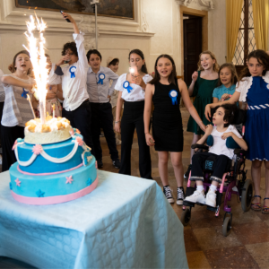 Sofia and her friends watch a sparkling candle burn on her tiered cake
