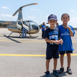 two boys stand in front of a helicopter