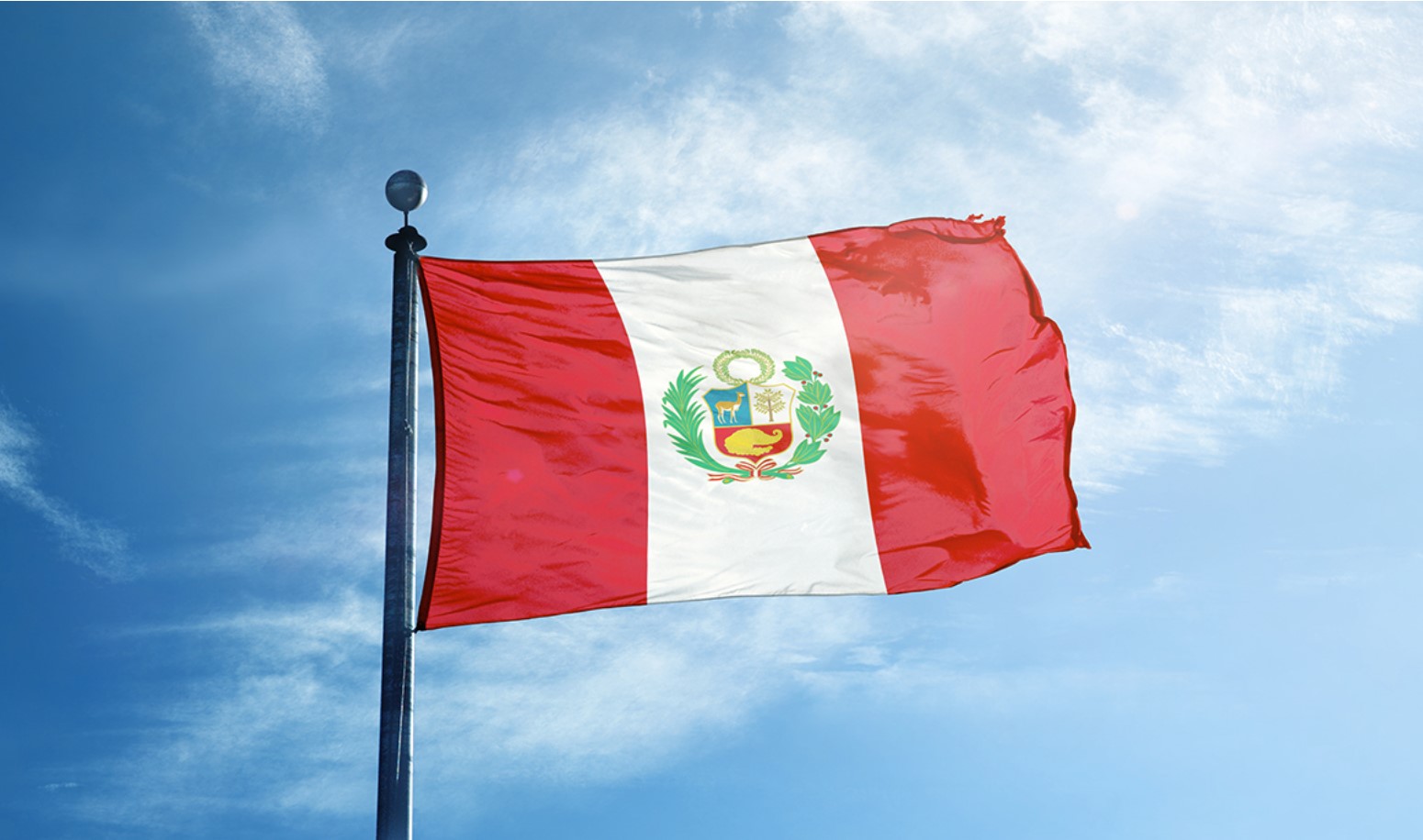 The peruvian flag flying over a blue sky
