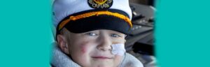 Wish child in sailor cap with nasal tube smiles at the camera