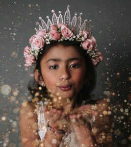 Wish child Khushi wears a crown and blows glitter at the camera