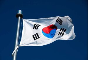 A picture of a Korean flag floating in front of a dark blue sky