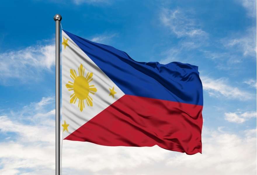 A flag of the Philippines floating over a blue sunset sky 