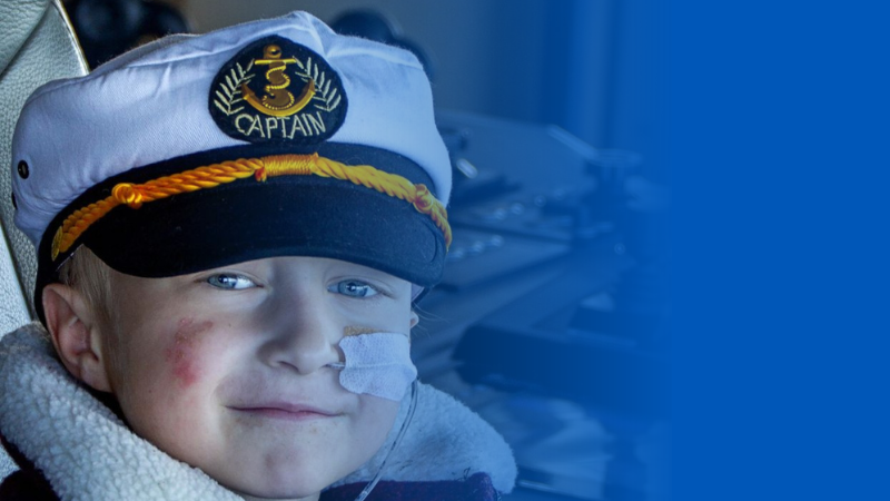 Wish child in sailor cap with nasal tube smiles at the camera