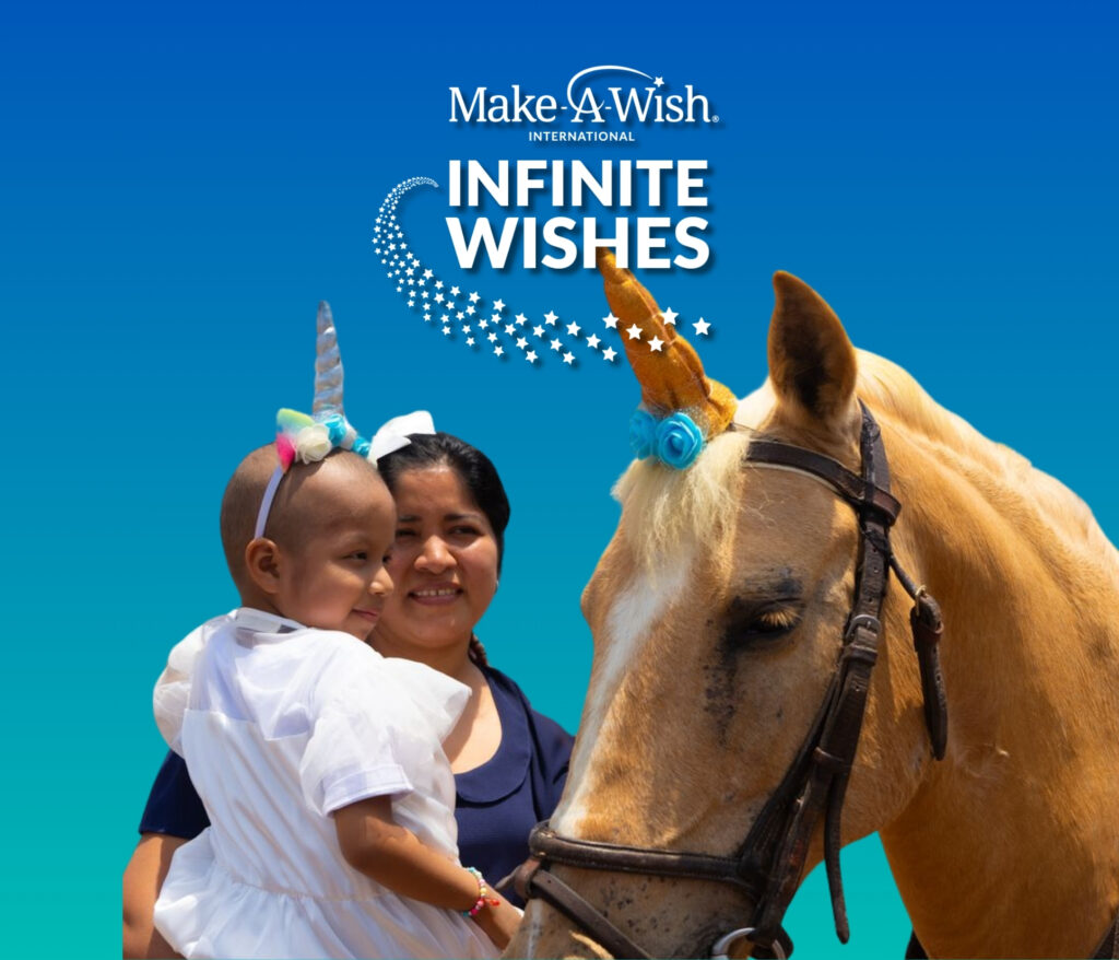 A smiling woman holds a child wearing a unicorn headband beside a light brown horse with a blue and gold unicorn horn, under the Make-A-Wish Infinite Wishes logo on a blue background—celebrating the magic of charity streaming.