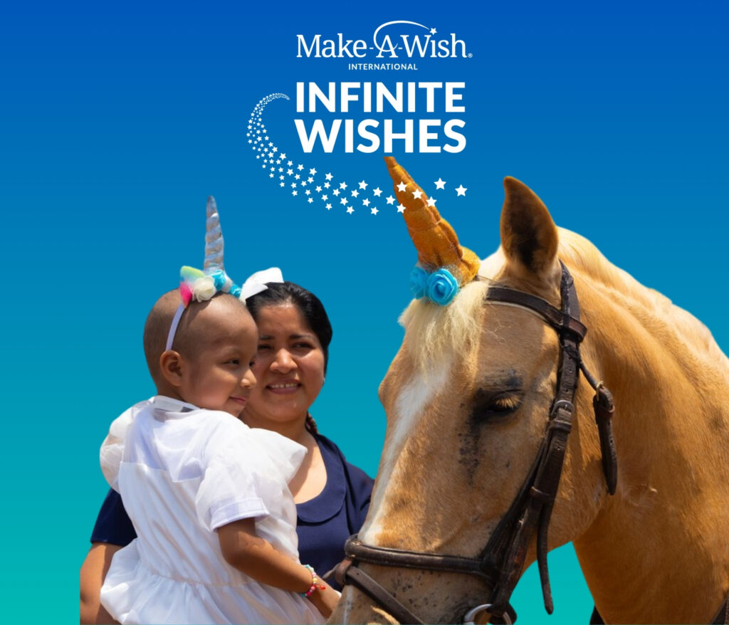 A smiling woman holds a young child wearing a unicorn headband beside a tan horse with a unicorn horn, set against a blue background with the Make-A-Wish Infinite Wishes logo, white stars, and charity streaming highlights.