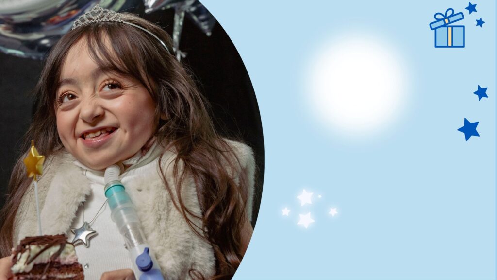 A smiling young girl with long brown hair, wearing a tiara and a star necklace, holds a fork with cake. She has a tracheostomy tube. The image has a blue background with stars and a gift box illustration on the right.