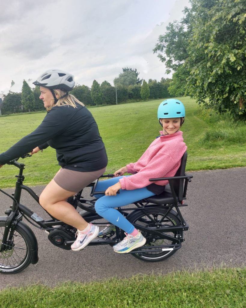 A woman and child on a bicycle, sharing laughter and joy, while Esmanur's wish to be a princess with a red dress sparkles in their imagination.