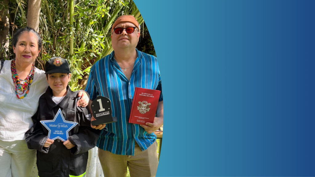 A smiling woman, a child in a black outfit holding a Make-A-Wish star and a number one trophy, and a man in sunglasses holding an award and a red book stand outdoors, with a blue gradient background on the right.