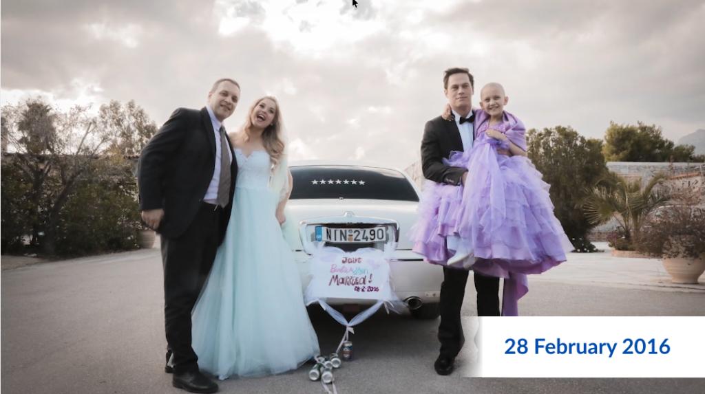 Two couples in formal attire stand in front of a white car decorated for a wedding. One man holds a child in a lavender dress, perhaps sharing Binaya’s wish to have a soft elephant toy on this special day. The date 28 February 2016 appears in the lower right corner.